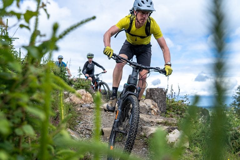 Man in yellow t-shirt mountain biking in Castlewellan near the Mourne Mountains